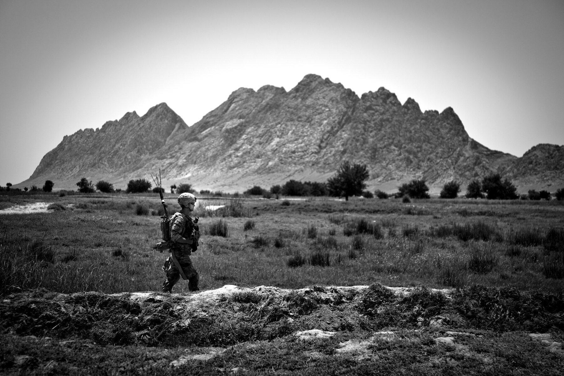 A lone soldier crossing a wide valley on patrol. U.S. Army (public domain, DVIDS).